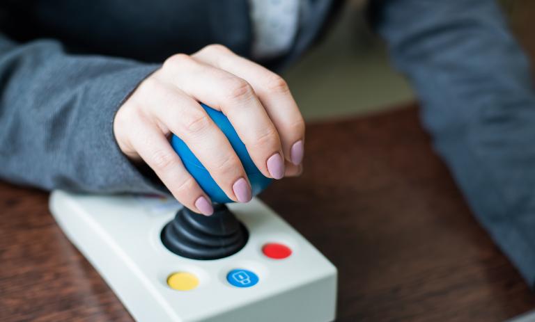 Closeup of a person with cerebral palsy working on a specialized computer mouse