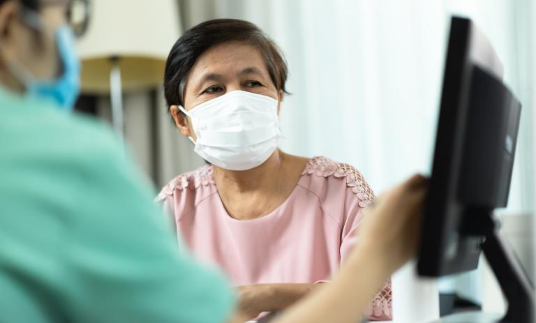 woman talking to nurse looking at computer screen