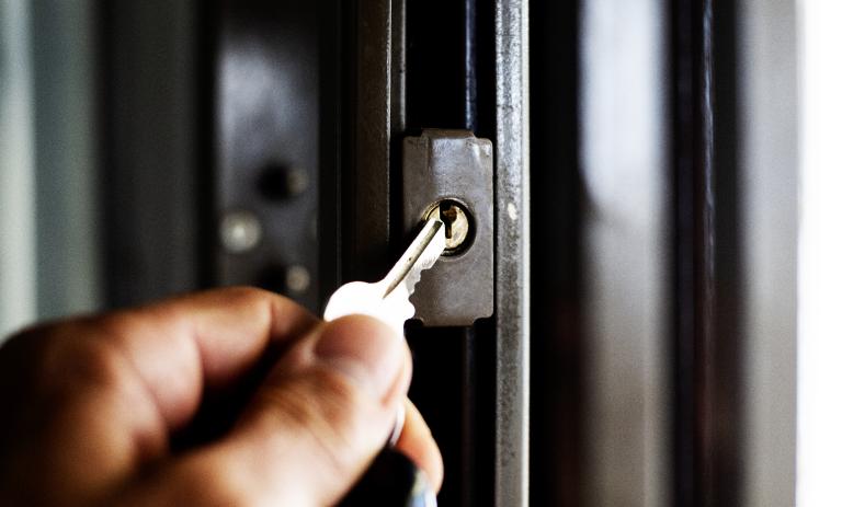 A close-up of someone holding a key to open a security gate.