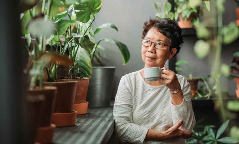 Senior woman sitting peacefully in an indoor garden.