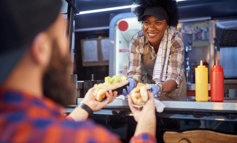 Food truck employee handing food to customer