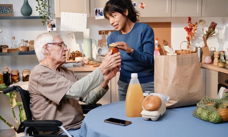 women handing juice over to elderly