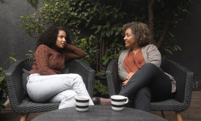 Daughter sitting on a patio having coffee with their mother