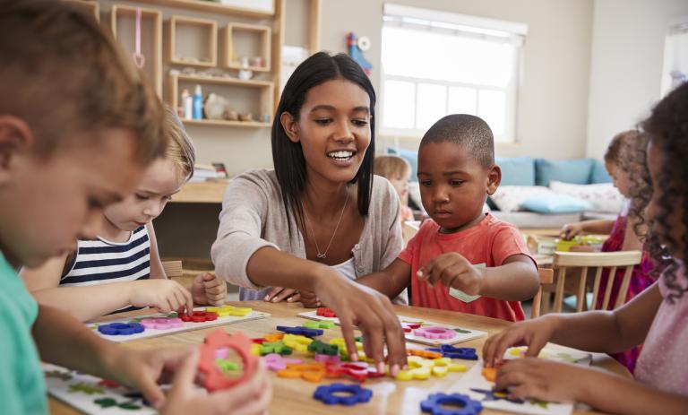 A child care provider does a craft with a group of children