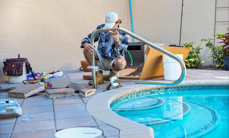 A construction worker modifying the railing of an outdoor pool