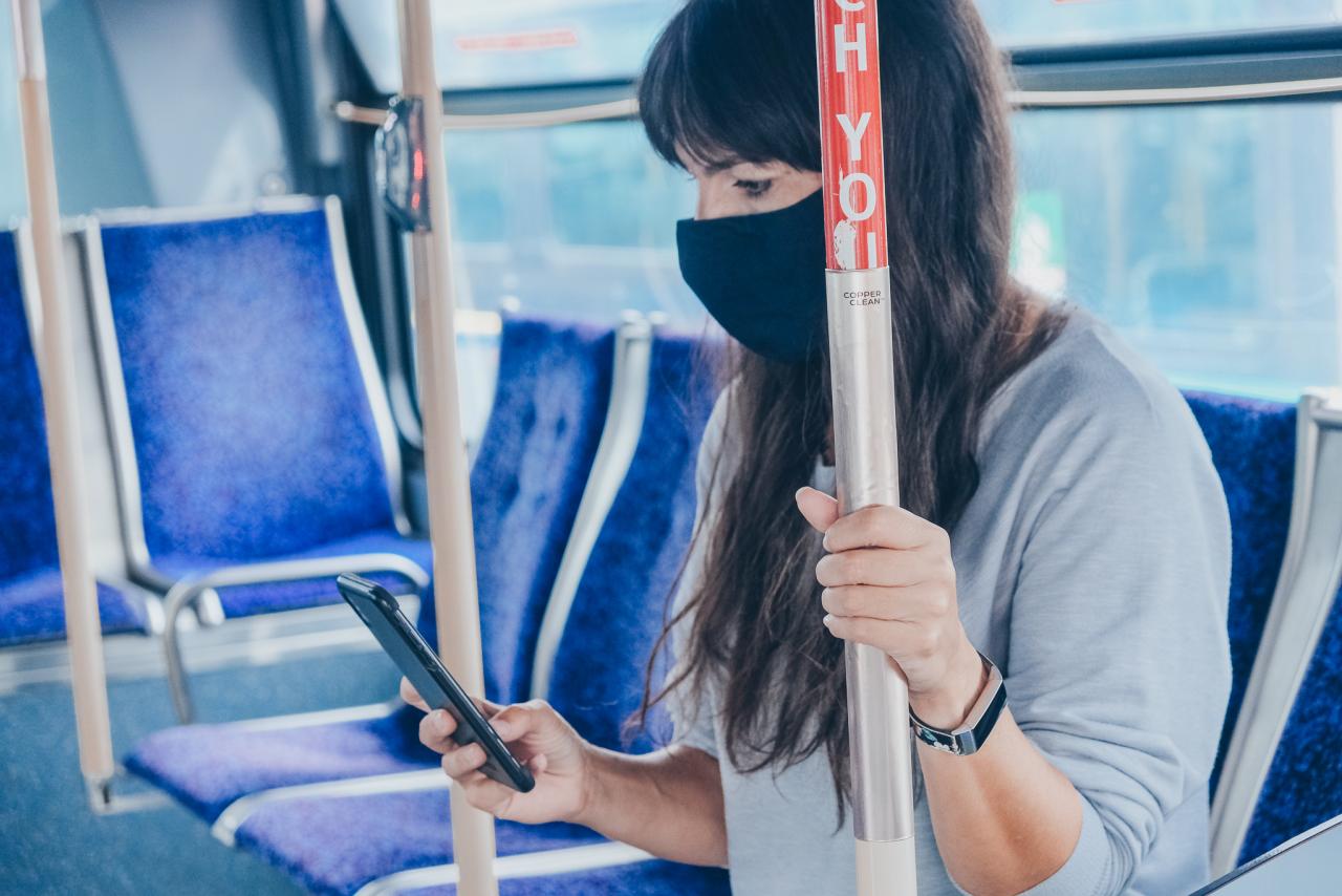 Person inside a bus holding on to a copper bar.