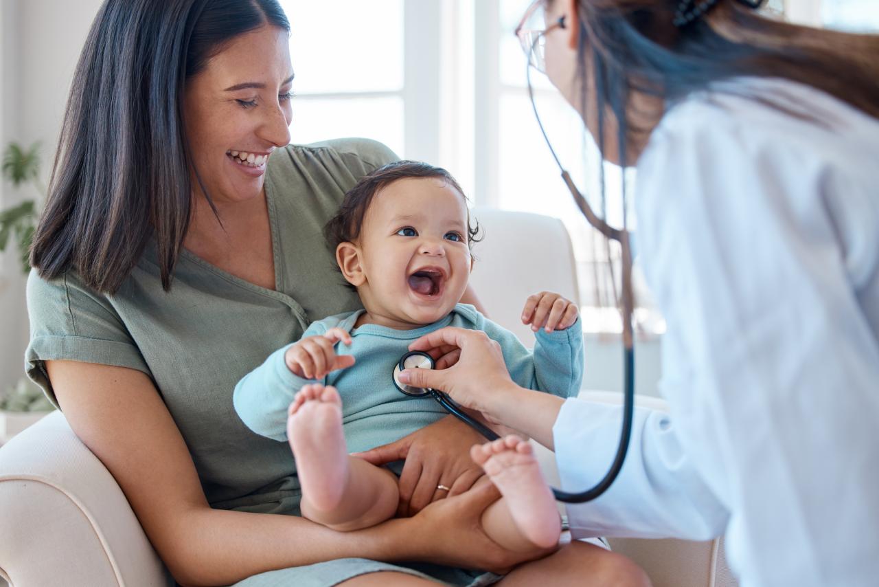 A child laughing while being checked by a doctor