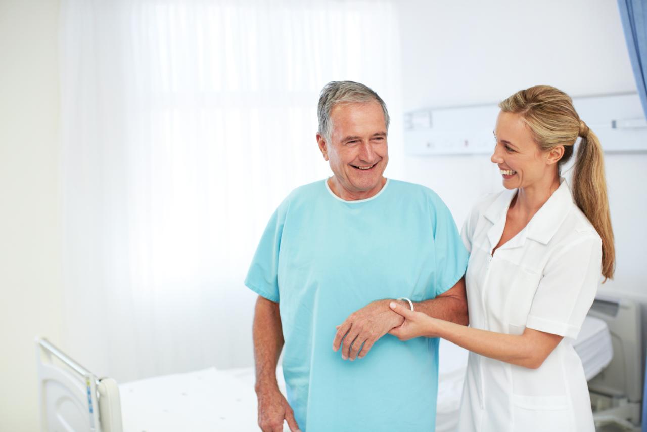 A smiling nurse aiding an elderly patient in a hospital ward