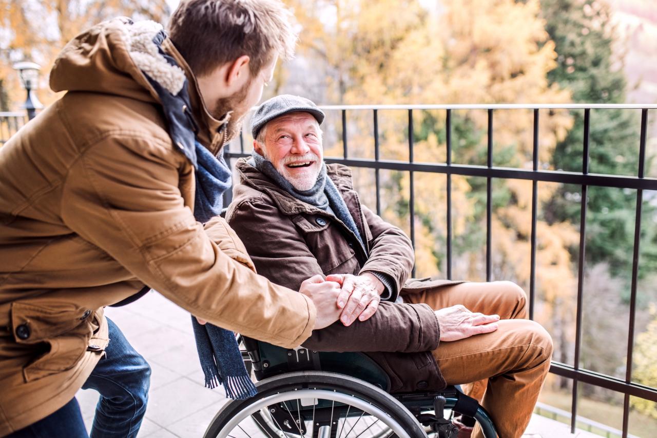 Father in wheelchair and young son relaxing on a balcony.