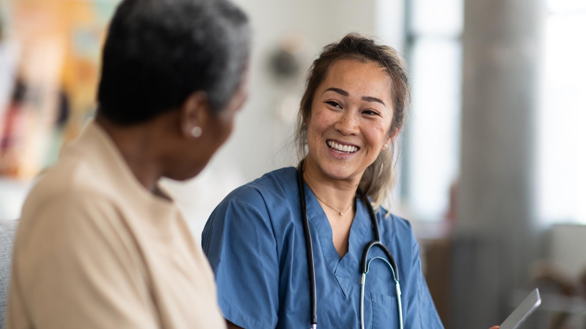 Smiling doctor speaking with patient while reviewing informatio on a clipboard