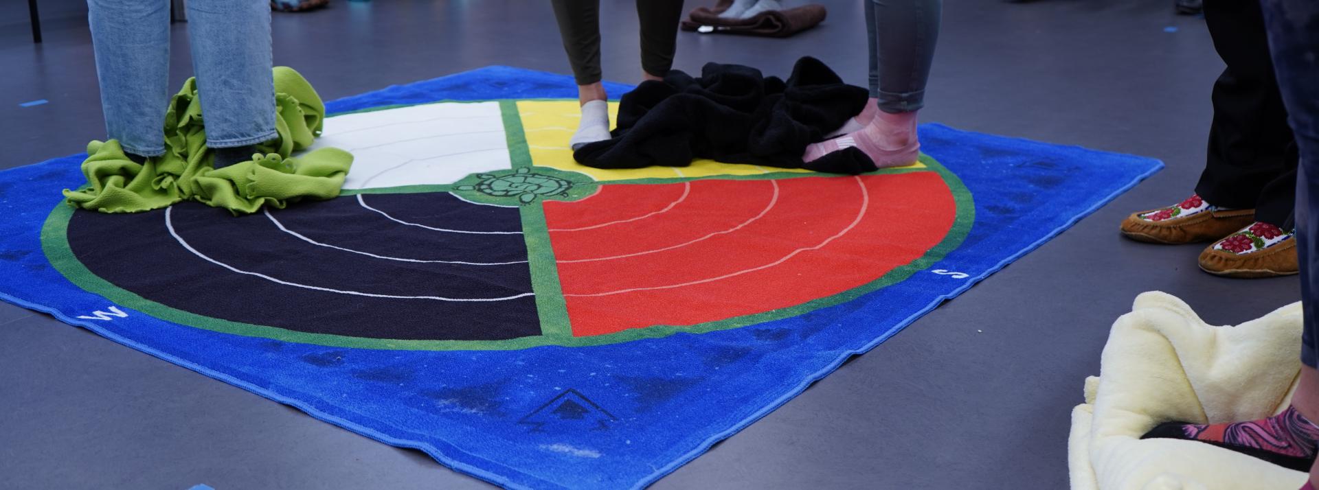 Three people standing on a blanket. 