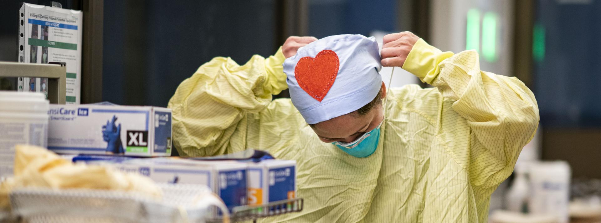 person with heart on cap putting on mask