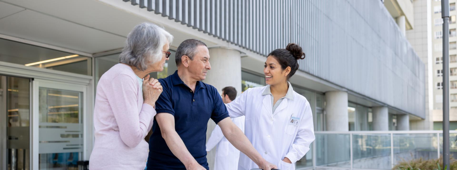 Doctor looking happy to see her patient walking with a walker after the hospital