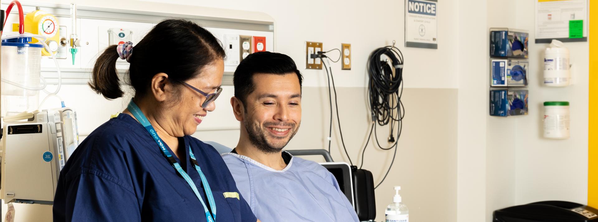 A food service staff member bringing a seated patient their meal in a hospital room.