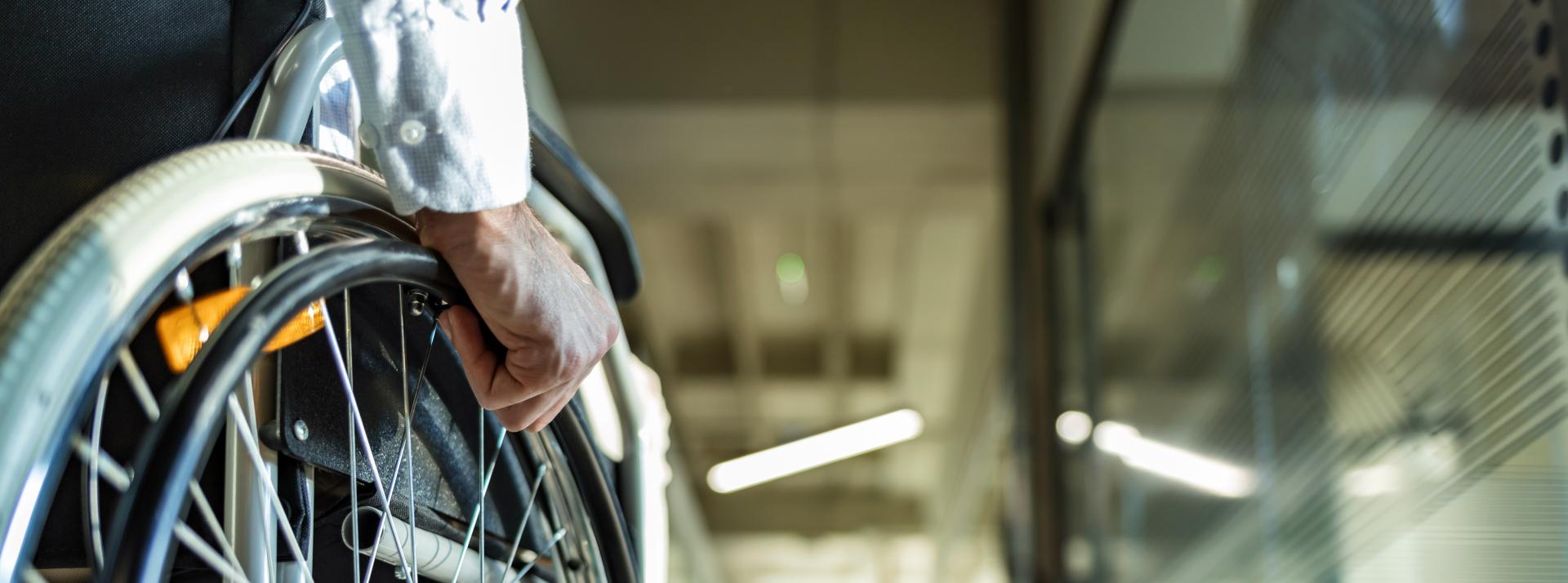 Close up of a person using a wheelchair in an office hallway