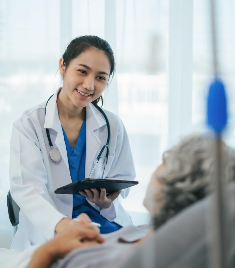 Doctor giving patient information while they lay in a hospital bed