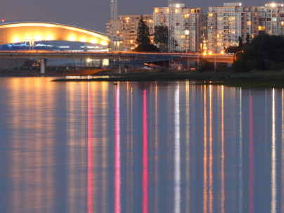 Richmond Olympic Oval lit up in background with river in front of the photo.