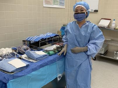 Mary Luu, LPN, standing in an operating room while wearing work scrubs.