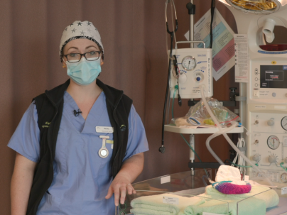 Nurse stands beside infant warmer