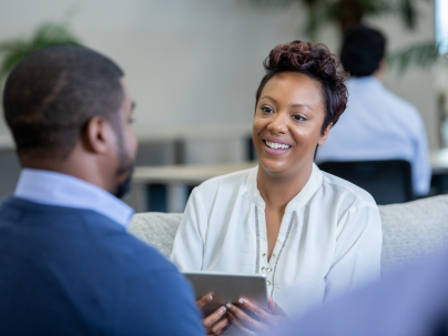 Person sitting with tablet device in their hand, looking at client speaking.