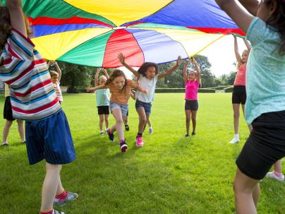 Children playing outside with a parachute