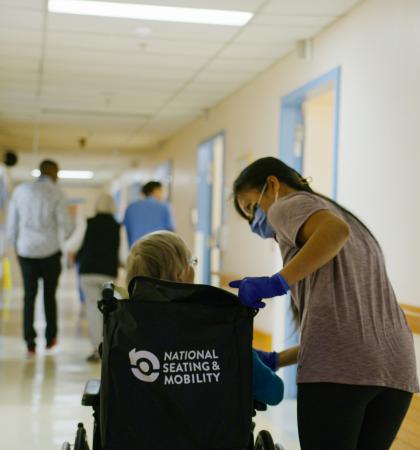 A staff member guides a patient in a wheelchair down the hallway of the interim home at George Pearson Centre